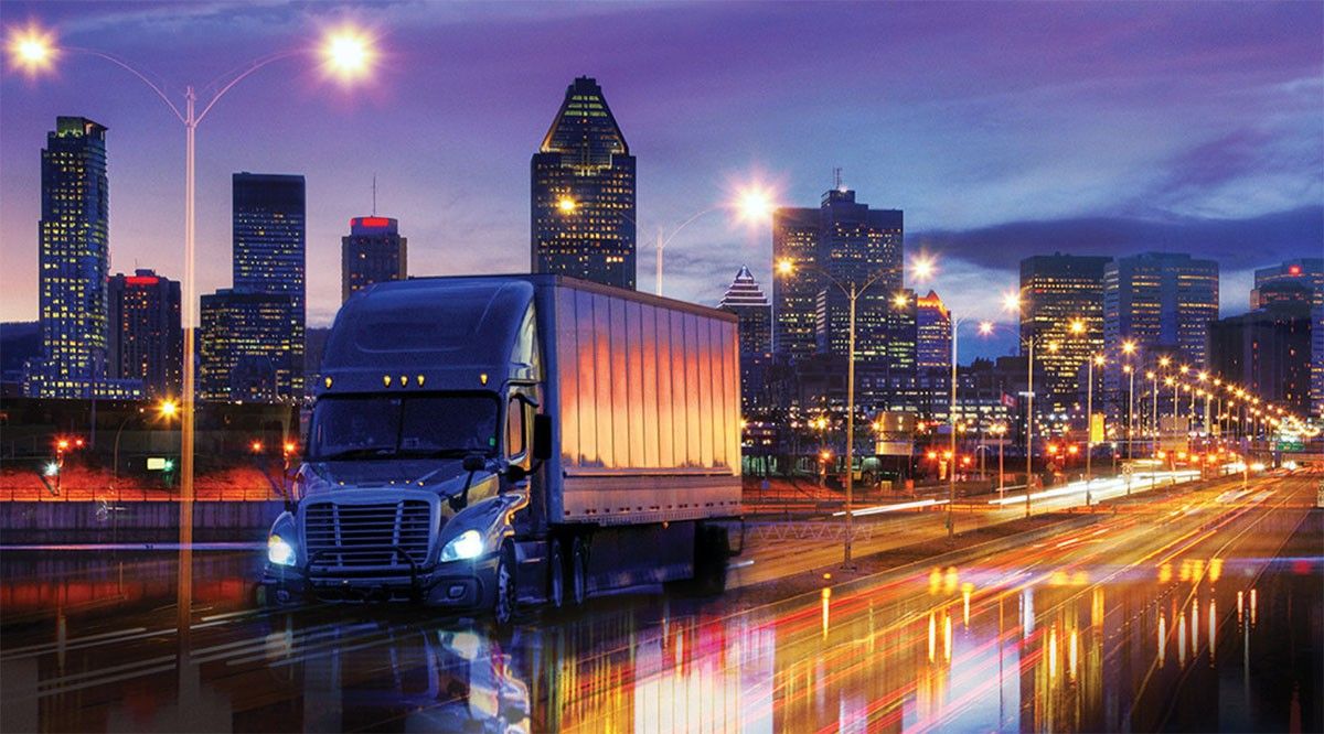 Truck driving in front of cityscape